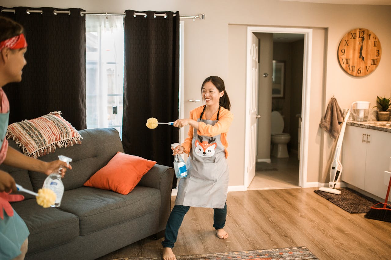 A cheerful couple engages in a playful cleaning session in their home.